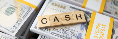 Wooden square blocks in form of word Cash on pack of dollarsの写真素材