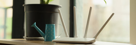 Wi-Fi router stands on table near pot-plant with big leavesの写真素材