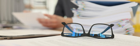 Glasses put on papers near stack of folders with documentsの写真素材