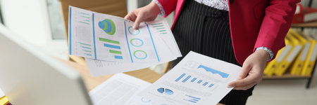Woman sorts document papers with statistics and diagramsの写真素材
