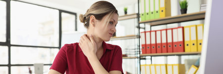 Woman employee suffers from pain in neck at office workplaceの写真素材