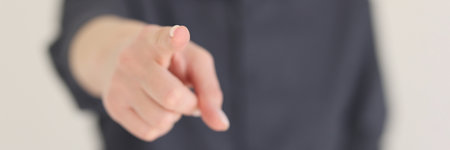Blurry woman points index finger to camera on beigeの写真素材