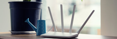 Wi-Fi router with antennas stands near lush plant in potの写真素材