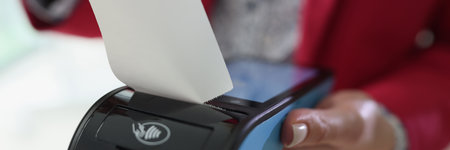 Woman holds terminal in hand tearing off purchase receiptの写真素材