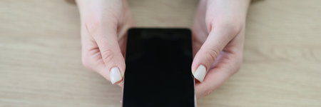 Woman in handcuffs holds modern smartphone sitting at tableの写真素材