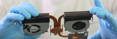 Master in rubber gloves holds cooling system of old laptopの写真素材