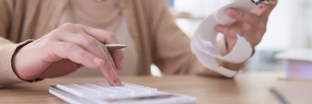 Mature woman makes counts from paper check using calculatorの写真素材