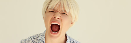Angry young woman with short haircut screams in studioの写真素材