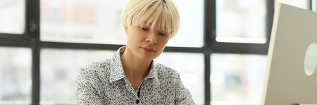 Woman turns pages of diary sitting at desk in office