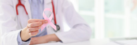 Doctor holds pink ribbon at appointment with patientの写真素材