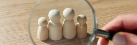 Woman looks at figures of family members through loupeの写真素材