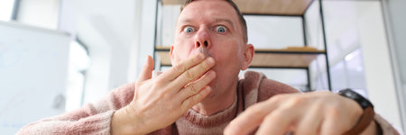 Shocked man covers mouth with hand opening eyes wideの写真素材