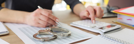 Handcuffs on investigation paper while woman making countsの写真素材