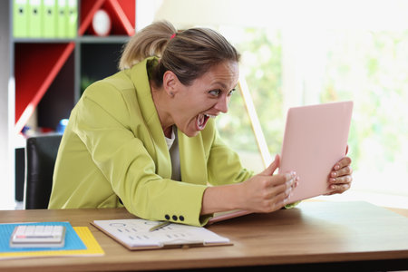 Very happy woman holds her laptop in hands above table and looking at screen.の写真素材