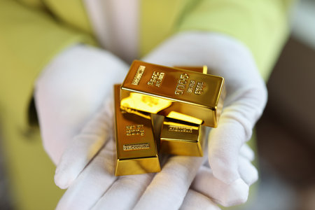 Gold bars in gloved hands close up.の写真素材