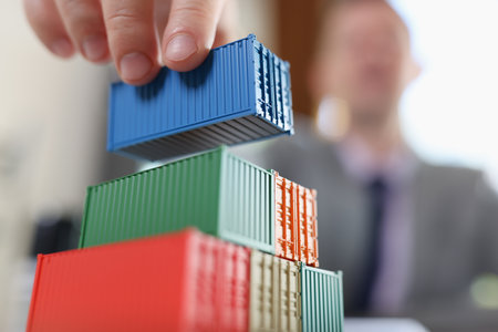 Business man arranging stack of freight containers on his table in office.の写真素材