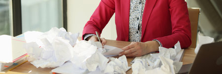 Serious concentrated business woman writing, crumpled paper on tableの写真素材