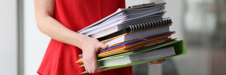 Secretary carries stack of folders with accounting materials