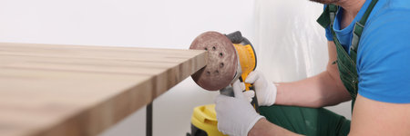 Concentrated worker polishes board edge with grinding toolの写真素材