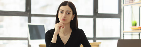 Pretty female worker looks forward at workplace in officeの写真素材