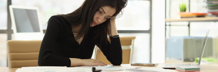 Upset office worker looks at wrong done report at deskの写真素材