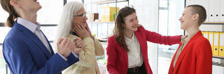 Happy coworkers share success with colleague in officeの写真素材
