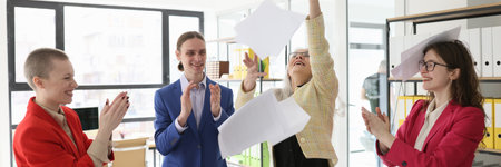 Mature employee throws up papers while colleagues applaudの写真素材
