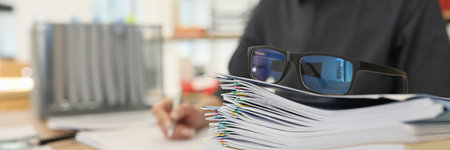 Glasses put on stack of folders with working documentsの写真素材