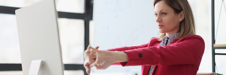 Lady manager stretches arms before starting work on computerの写真素材