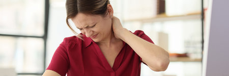 Woman worker suffers from pain in neck at office workplaceの写真素材