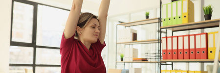 Tired woman stretches back and arms after finishing reportの写真素材