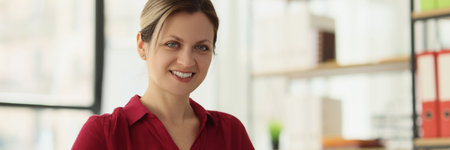 Happy female employee holds clipboard sitting at tableの写真素材