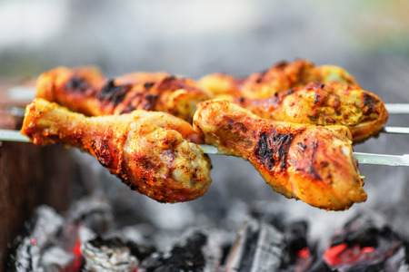 Chicken legs being roasted over charcoalの写真素材