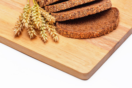 Slices of rye malt bread and wheat ears on the chopping boardの写真素材