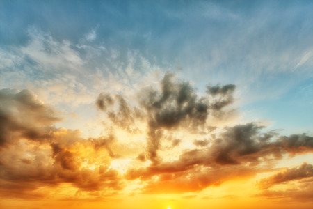 Cumulus sunset clouds with sun setting downの写真素材