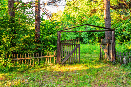 Old wooden gate with cross at top in forestの写真素材