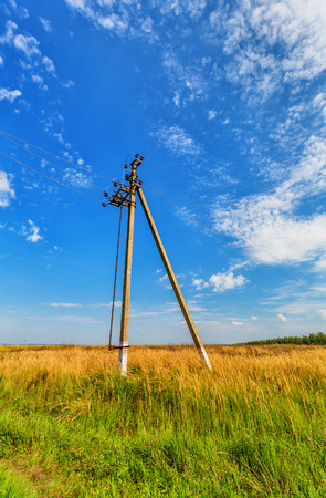 Powerline beneth blue sky with cumulus cloudsの写真素材