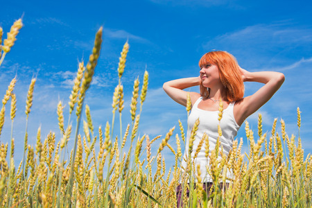 Beautiful young woman at wheat field in summer dayの写真素材
