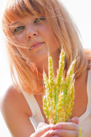 Beautiful young red-haired woman with the ears of wheatの写真素材