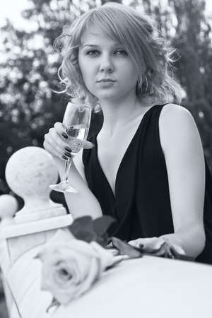 Beautiful woman drinking champagne from wineglass in black and white with soft blue tintの写真素材