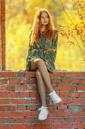 Teen girl in dress sitting on brickwork in abandoned place. Shallow dofの写真素材