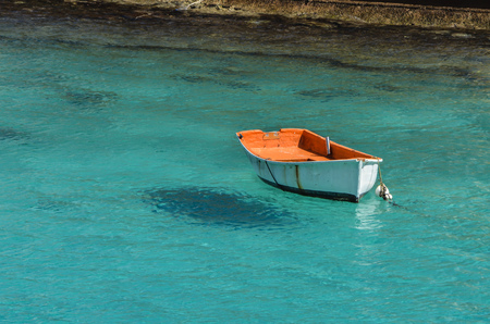 White and orange boat floating in calm turquoise waterの写真素材