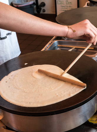 crepe being spread by a crepe maker in a crepe shopの写真素材