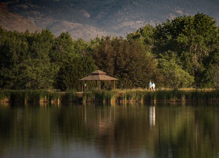 An older couple taking a morning walk around a lake with reflectionの写真素材