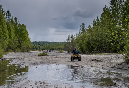 Dad and son riding their ATV through water and sandの写真素材