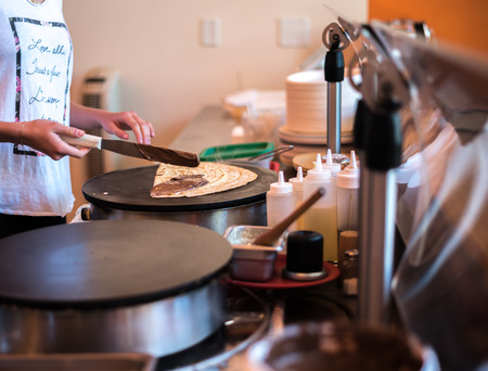 crepe being spread with chocolate in a creperyの写真素材