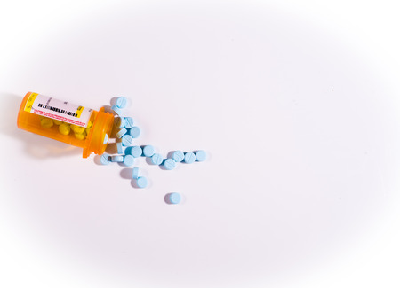 pill bottle spilling out blue pills, medicationの写真素材
