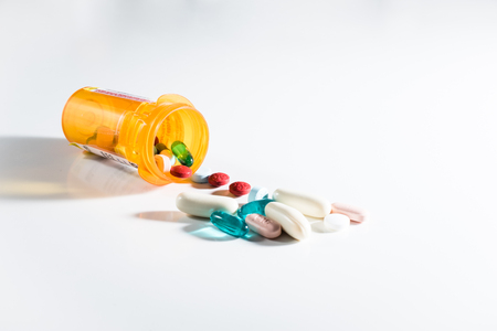 Variety of medications spilling out of a pill bottle on its sideの写真素材