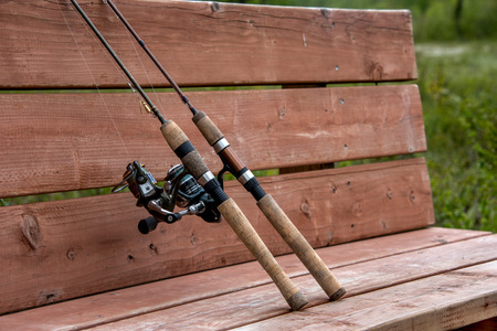 Two fishing poles close up on a benchの写真素材