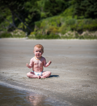 Baby at the beach in meditation poseの写真素材